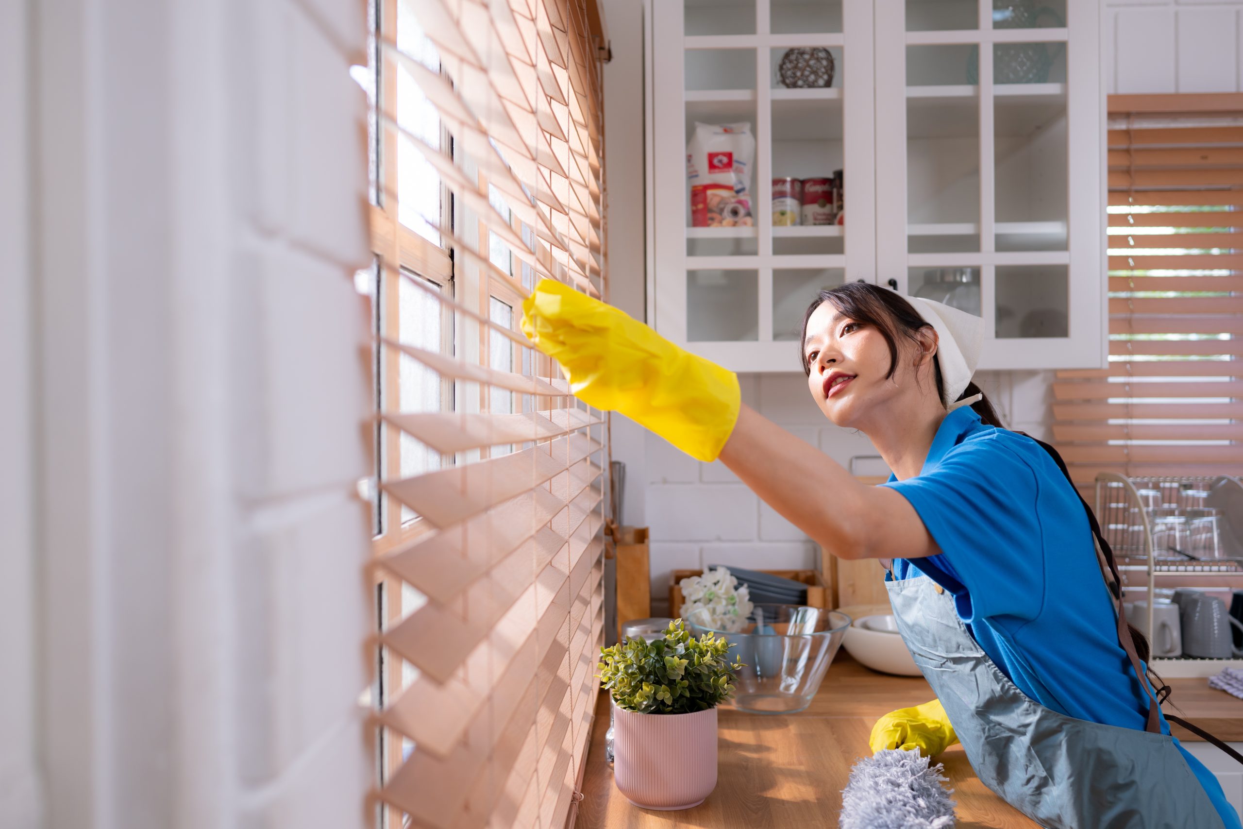 Asian young woman cleaning window in the kitchen. housework conc