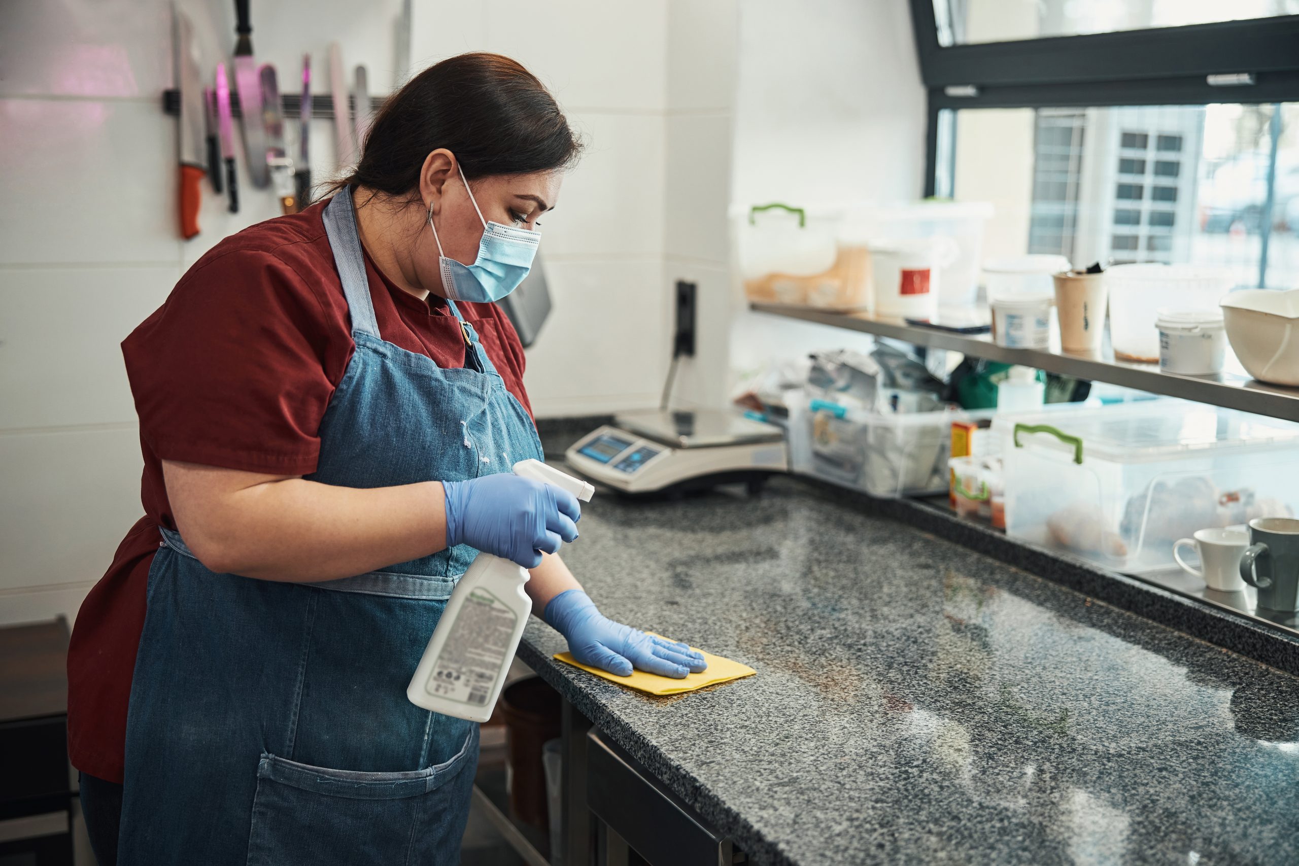 Hard-working cafe worker cleaning and sanitizing kitchen surfaces
